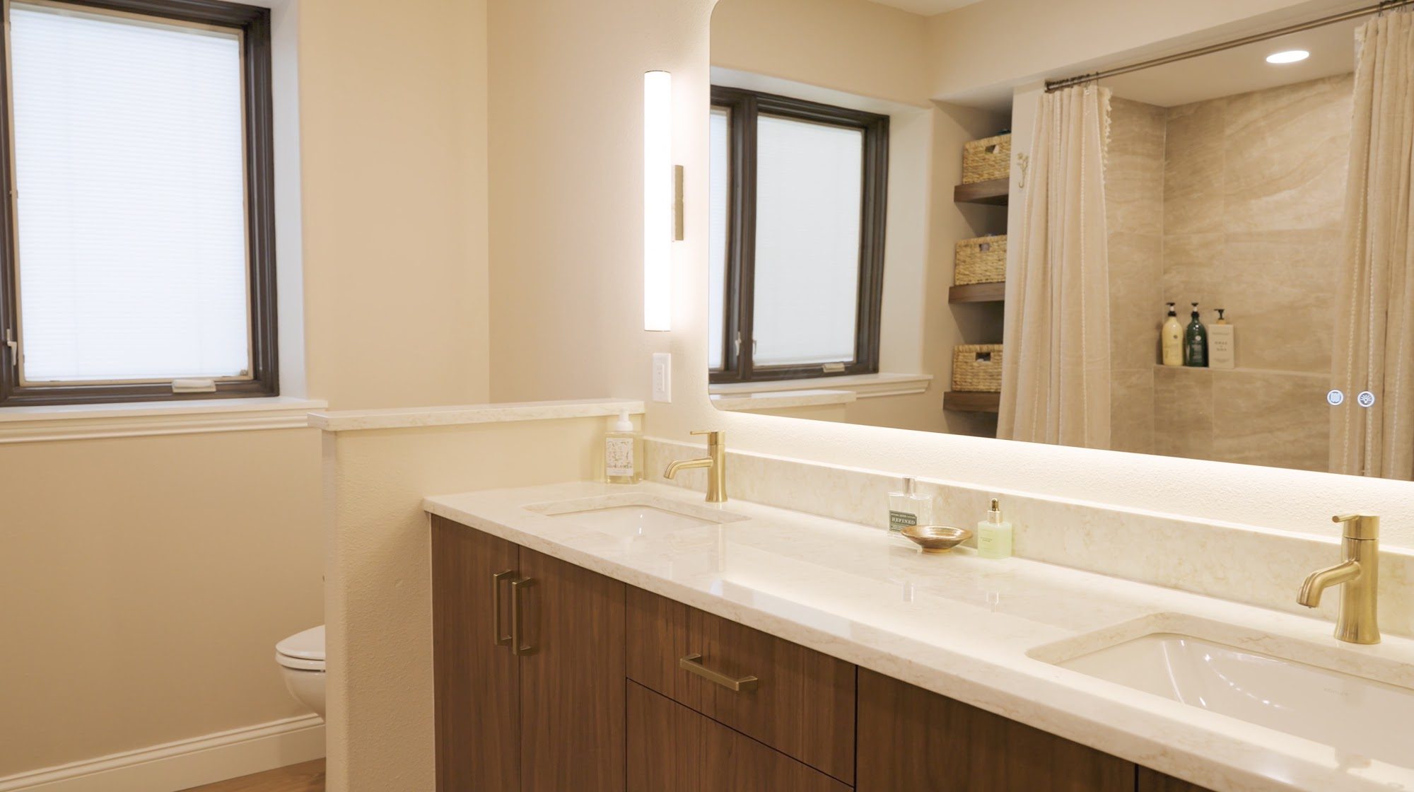 Basement bathroom with a double vanity, quartz top, backlit mirror and sconce lights
